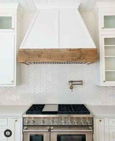 a stove top oven sitting inside of a kitchen next to white cupboards and cabinets