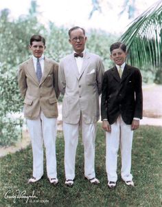 three men in suits and ties standing next to each other on the grass near trees