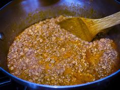 a wooden spoon in a pot full of food on the stove top with some oil