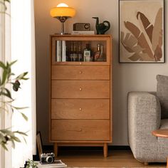 a living room scene with focus on the chest of drawers and chair in the foreground