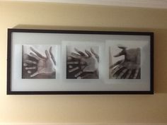 three hand prints in a black frame hanging on the wall