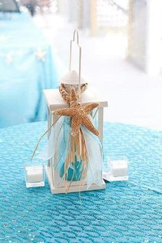 a starfish themed candle holder on a blue tablecloth with white and gold decorations