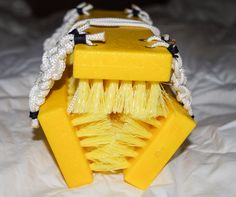 a close up of a yellow brush on a white bed sheet with some string attached to it