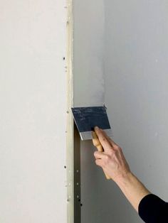 a person holding a paint roller in front of a wall