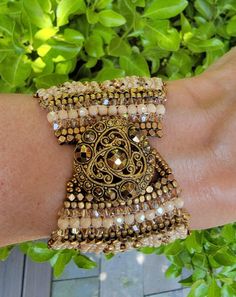 This ivory Swarovski Pearl and Crystal Cuff is sewn with 19 rows of golden ivory beads. Swarovski pearls and crystals are channel set in 4 central rows. The edges of the piece are sewn with a combination of glass and brass hand carved mini cube beads with pale golden swarovski crystals and complementing ivory glass faceted mini beads. The center section of the piece mirrors this design.  The cuff is finished with a gorgeous 19th century antique golden filagree button.  This piece measures 1& 3/4 Elegant Beaded Cuff Bracelets, Gold Beaded Cuff Jewelry, Elegant Beaded Cuff Jewelry, Gold Beaded Cuff Bracelets, Elegant Adjustable Cream Cuff Bracelet, Elegant Beaded Cuff Bracelet For Wedding, Elegant Cream Adjustable Cuff Bracelet, Gold Embellished Jewelry For Formal Occasions, Elegant Beige Beaded Bracelets