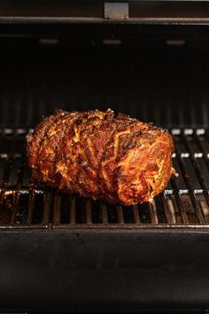 a piece of meat is cooking on the grill in an open oven, it appears to be roasting