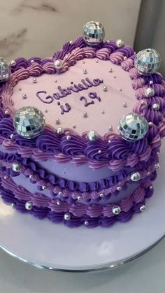 a heart shaped cake with purple icing and silver decorations on it's edges