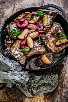 a pan filled with meat and vegetables on top of a wooden table