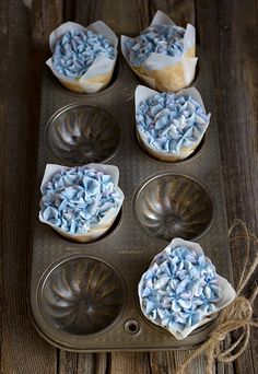 cupcakes with blue frosting in a muffin tin on a wooden table