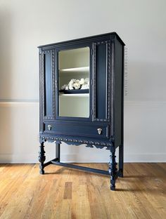 a blue cabinet with a mirror on the top and shelves above it, sitting on a hard wood floor