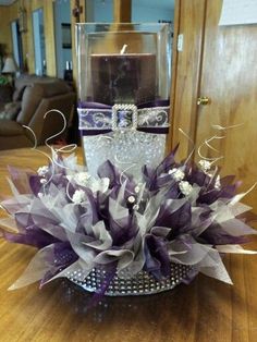 a glass vase filled with purple flowers on top of a wooden table