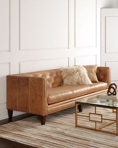 a brown leather couch sitting next to a glass table