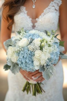 a bride holding a bouquet of blue and white flowers