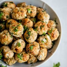 a white bowl filled with meatballs covered in parsley