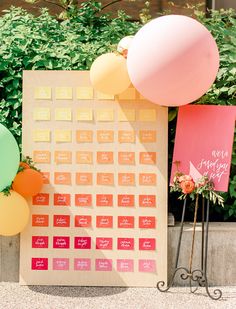 a table with balloons and a calendar on the wall in front of some shrubbery