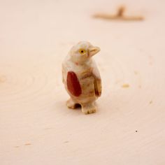 a small toy bird sitting on top of a wooden table