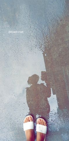 a person standing in front of a puddle with their shadow on the wet ground next to them