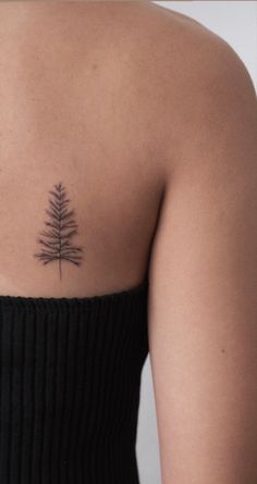 a woman's back with a small tattoo on her left shoulder and a pine tree in the middle