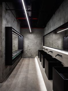 a row of sinks in a public restroom with mirrors on the wall and lights hanging from the ceiling