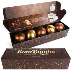 a box of chocolates with gold foiled balls in it's display case