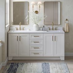 a bathroom with two sinks, mirrors and rugs on the floor in front of it