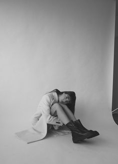 a black and white photo of a woman sitting on the floor with her legs crossed