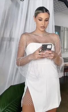 a woman in a white dress looking at her cell phone