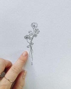 a hand is pointing at a flower on a piece of paper that has been drawn