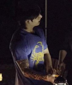 a young man with tattoos on his arm holding a hot dog in front of him