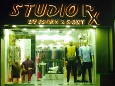 a store front with mannequins and clothes on display in the window at night