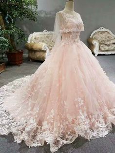 a pink wedding dress on display in a room with white couches and potted plants