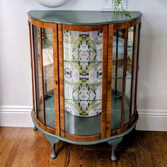 a wooden cabinet with glass doors and flowers on it