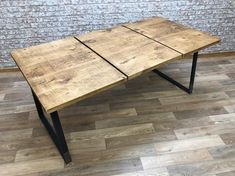 a wooden table sitting on top of a hard wood floor next to a brick wall