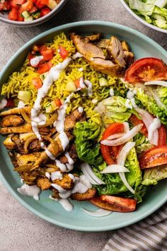 a bowl filled with salad and dressing next to two bowls full of food on the table