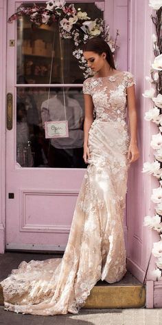 a woman standing in front of a pink door wearing a dress with flowers on it