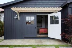 a small gray house with a red bed in the doorway and an awning over it