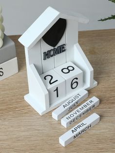 a white house shaped clock sitting on top of a wooden table