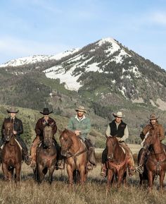 a group of men riding on the backs of brown horses in front of a snow covered mountain