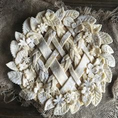 an intricately designed piece of food on a tablecloth with some tassels around it