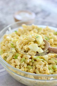 a bowl filled with macaroni salad and a wooden spoon