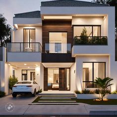 a white car parked in front of a two story house at night with lights on