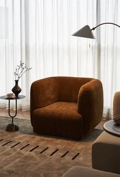 a living room filled with furniture next to a window covered in sheer curtained drapes