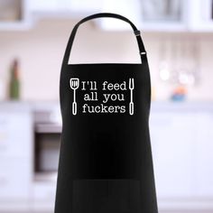 a black apron that says i'll feed all you fukers on the front