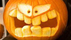 a carved pumpkin with an angry face on it's side and teeth in the middle