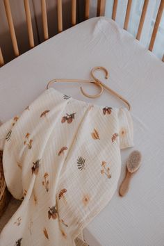 a baby's crib with an unmade blanket and brush next to it