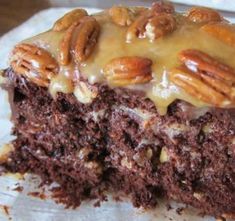 a close up of a piece of cake on a plate with pecans and icing