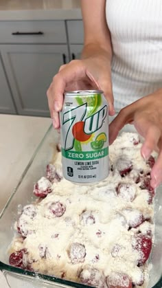 a woman is spreading icing on a cake with cranberries and powdered sugar