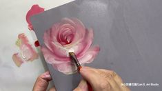 someone is painting a flower on a piece of paper