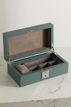 an open green box sitting on top of a white marble counter next to a pair of scissors