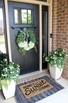 two planters with wreaths are on the front door and one has a welcome mat that says home sweet summer